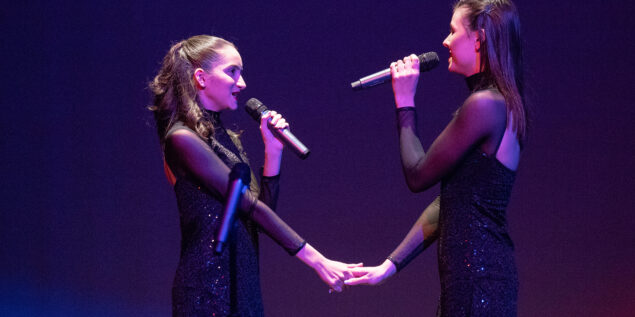 two girls holding hand of each other and singing