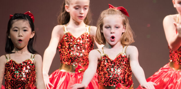 Young girls performing in sparkly red costumes.
