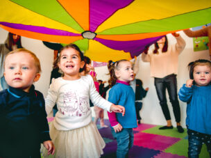 Group of babies under colorful sheet